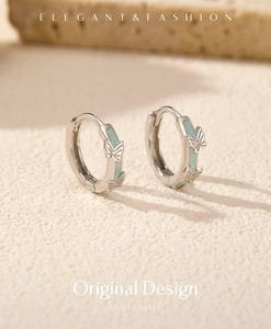 Close-up of s925 silver hoop earrings with mint green enamel and butterfly pattern detail