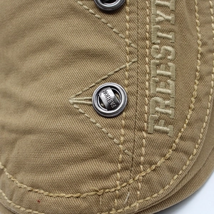 Detail of khaki canvas beret with freestyle embroidery and fashion metal button eyelet