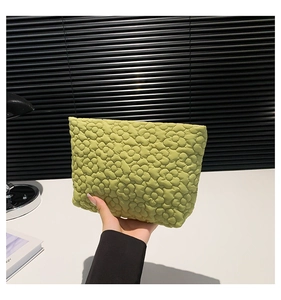 Detail of yellow-green quilted makeup bag featuring 3D floral stitching and soft fabric texture