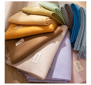 Close-up of colorful cashmere-feel scarves stacked in a fan shape on wooden floor