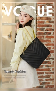 Close-up of black quilted leather shoulder bag featuring elegant golden chain straps