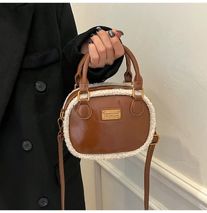 Detail of a brown leather pillow bag with white faux fur trim and gold metal hardware