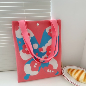 Detail of pink knitted tote bag with blue floral pattern and magnetic snap closure