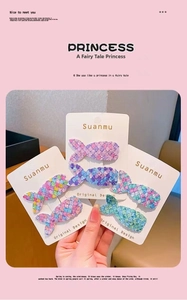 Détail de pinces à cheveux sirène avec paillettes colorées sur une carte blanche