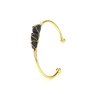 Detail view of handmade gold wire-wrapped bracelet with three black raw crystal stones