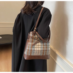 Detail of tweed checkered tote bag with brown leather straps and metal buckle accents