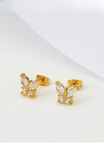Macro detail of gold butterfly stud earrings with sparkling cubic zirconia crystals