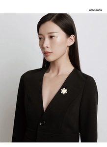 Close-up of a snowflake brooch in cream white on a black suit lapel for Christmas