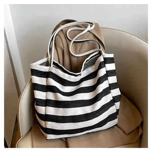 Close-up of black and white striped canvas tote bag placed on a beige leather chair