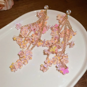 Detail view of pink flower tassel earrings with zircons on a white display plate