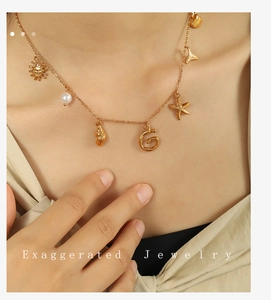 Detail of 18K gold-plated bamboo-style letter G pendant necklace with seashell charms
