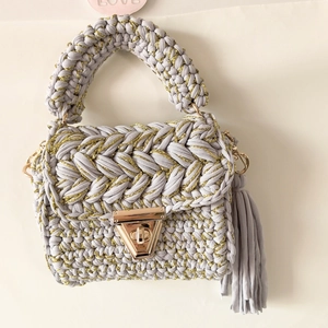 Detail of grey handmade crochet crossbody bag with metallic yarn and gold clasp lock