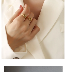 Close-up of a model wearing a gold knotted titanium steel ring with a cream blazer