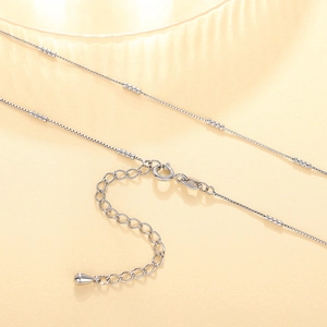 Detail of silver box chain necklace with textured beads, lobster clasp and extension link