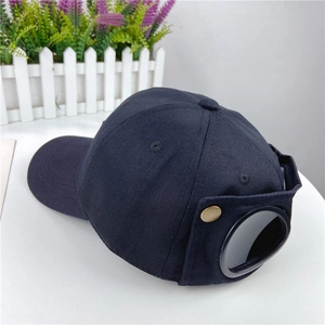 Detail of black cotton aviator baseball cap featuring back goggles and gold metal button