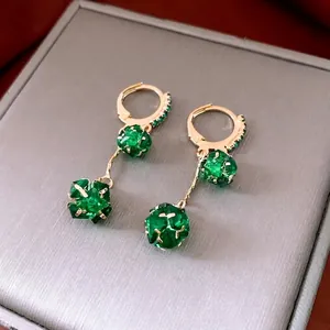 Elegant gold earrings featuring emerald green spherical stones with faceted crystal cuts