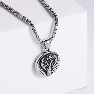 Detailed close-up of a silver stainless steel snake pendant on a white geometric stone