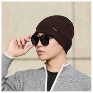 Detail of a brown ribbed knit beanie with a small metallic logo label for outdoor warmth