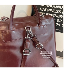 Detail of silver metal buckle and adjustable shoulder strap on burgundy leather bag
