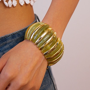 Macro detail of wide olive green resin bracelet with gold metallic segments on wrist