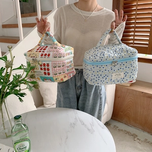 Détail de trousses de maquillage en coton matelassé avec motifs floraux et double zip