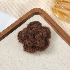 Macro detail of a 7cm brown crochet 3D flower accessory on a rustic wooden tray