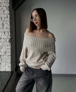 Close-up of off-the-shoulder neckline and soft ribbed knit texture on beige sweater