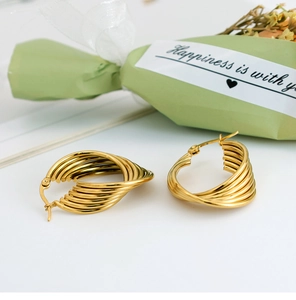 Detail of gold U-shaped earrings with multilayered twisted lines and polished finish