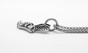 Détail macro du pendentif chaussure ailée en acier argenté sur une chaîne maille