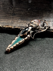 Macro shot of vintage bronze pendant featuring agate arrow and amethyst crystal details