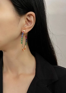 Detail view of large gold hoop earrings with multi-colored teardrop zircon stones on model
