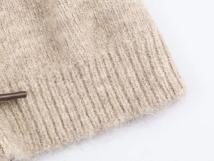 Macro della trama in maglia a coste beige e dettaglio della chiusura marrone scuro
