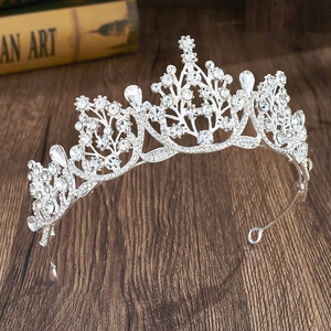 Detail of silver crown with teardrop crystals on dark wood background for weddings