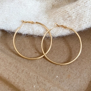 Detailed view of polished gold hoop earrings resting on soft white faux fur background