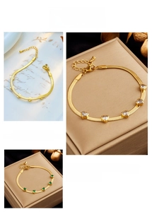 Detail of gold snake chain bracelet featuring heart-shaped clear and green zircon stones