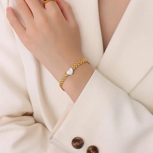 Elegant gold chain bracelet with heart-shaped mother of pearl on a wheat leaf texture