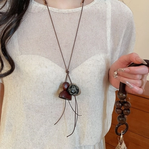 Detail of vintage necklace with wood and marble beads on a white knit sweater background