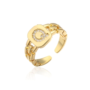 Macro view of adjustable gold letter G ring with chain texture and zircon inlay