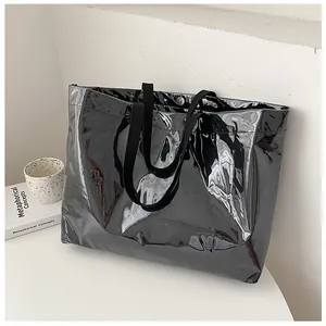 Detail of glossy black patent leather tote bag with wide strap for office and daily wear