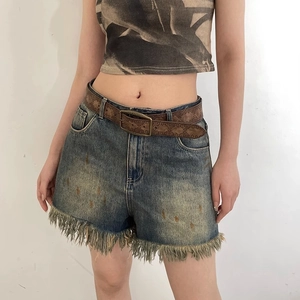 Blue denim shorts with frayed hem and distressed details paired with a vintage brown belt