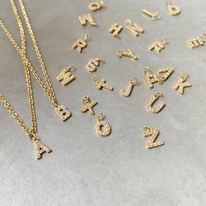 Detailed view of gold-plated alphabet pendants with sparkling zircon crystal inlays