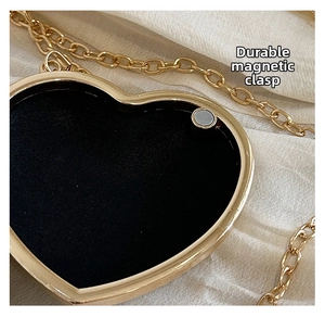 Détail du sac coeur avec fermeture magnétique, cadre en métal doré et doublure noire