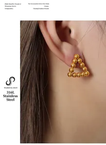Detail of 18k gold plated surgical titanium steel triangular bead stud earrings on model