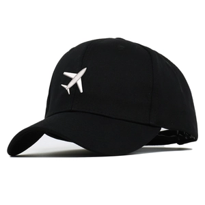 Close-up of white airplane embroidery on a black cotton baseball cap with six-panel crown