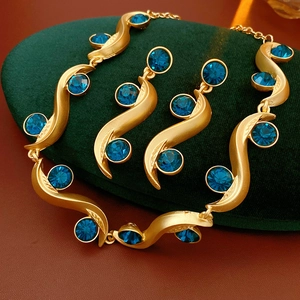 Detail of vintage gold wave jewelry set with blue round gemstones on green velvet padding