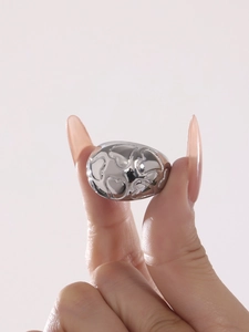 Close-up of a chunky silver heart ring with a polished metallic finish on fingers