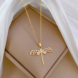 Close-up of a gold dragonfly pendant with crystals in a beige jewelry box
