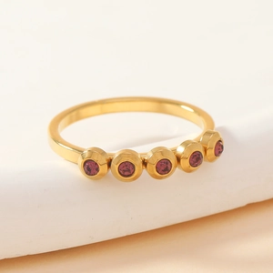 Macro shot of gold stainless steel ring featuring five purple stones in bezel setting