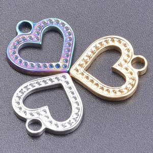 Three heart-shaped stainless steel pendants in silver, gold, and rainbow finish with crystals
