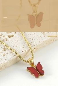 Detailed shot of red butterfly pendant with gold twist chain on textured white stone